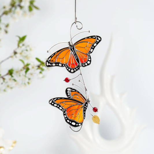 Two orange monarch butterflies crafted from stained glass with black and white details.