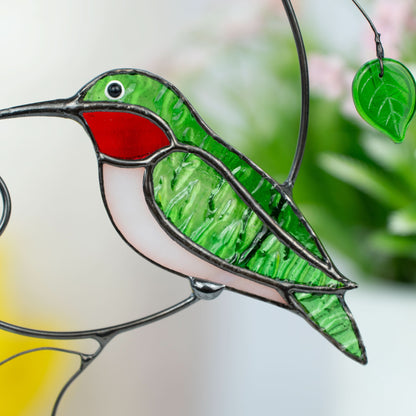Close-up view of green and red glass hummingbird with light belly.