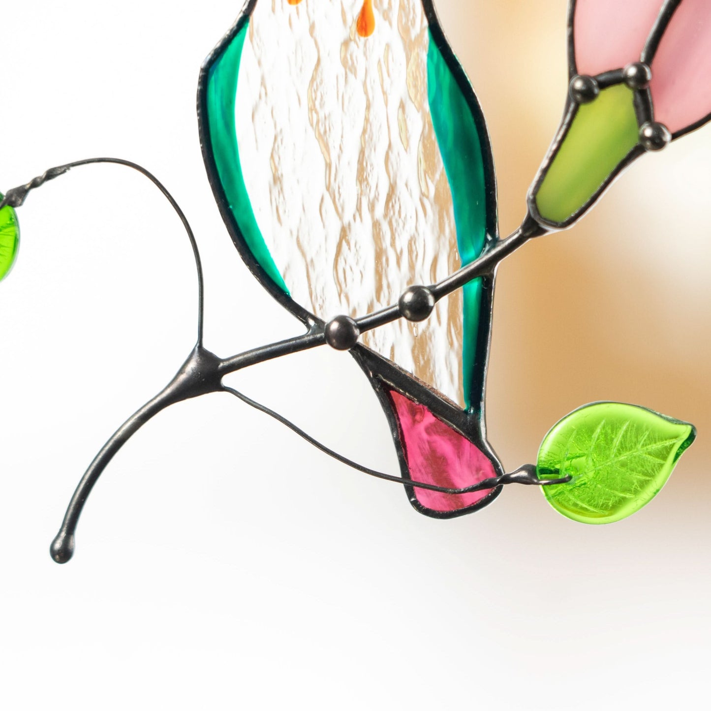 Close view of tail and leaves on hummingbird stained glass suncatcher showing craftsmanship and detail.