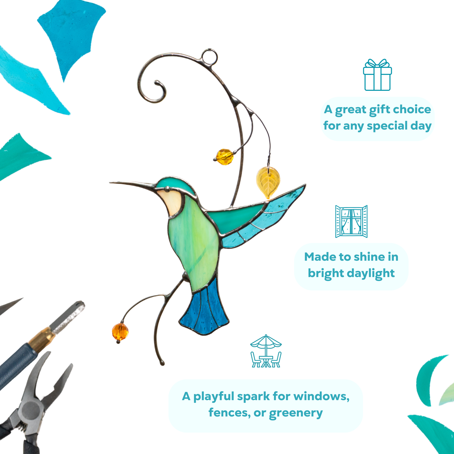 A delicate glass hummingbird with yellow beads hanging in a window with greenery in the background
