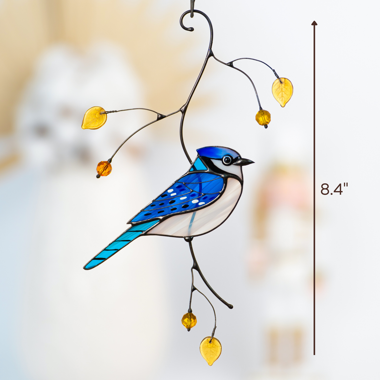 Stained glass blue jay hanging indoors near a blurred background, with height measurement of 8.4 inches.