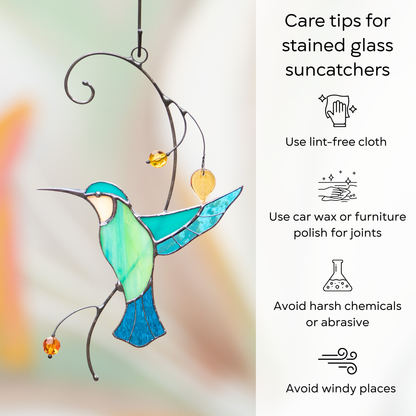A stained glass hummingbird in turquoise shades with hanging beads and leaves, displayed with care instructions on the side