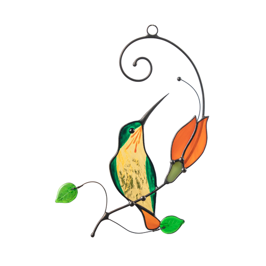 Stained glass hummingbird in green and light orange sitting on a branch with bright orange flower and green leaves