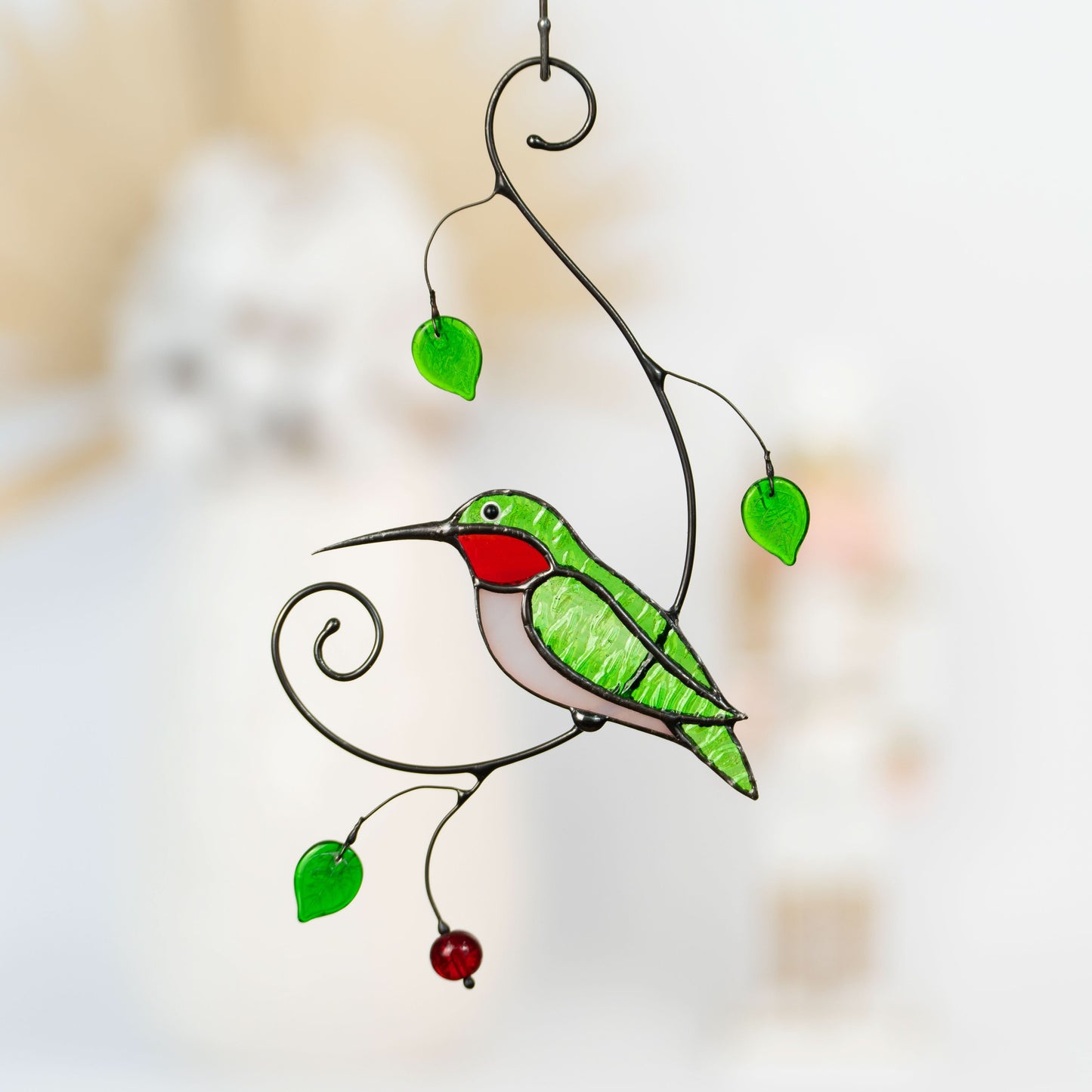 Green hummingbird suncatcher with red throat and green leaves.