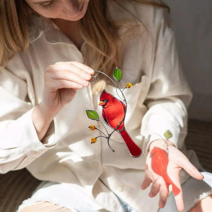 Woman holding a red cardinal stained glass bird suncatcher with a blurred background