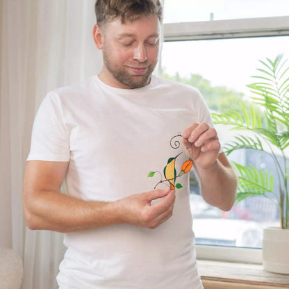 Man holds stained glass orange hummingbird suncatcher, ready to hang on a window