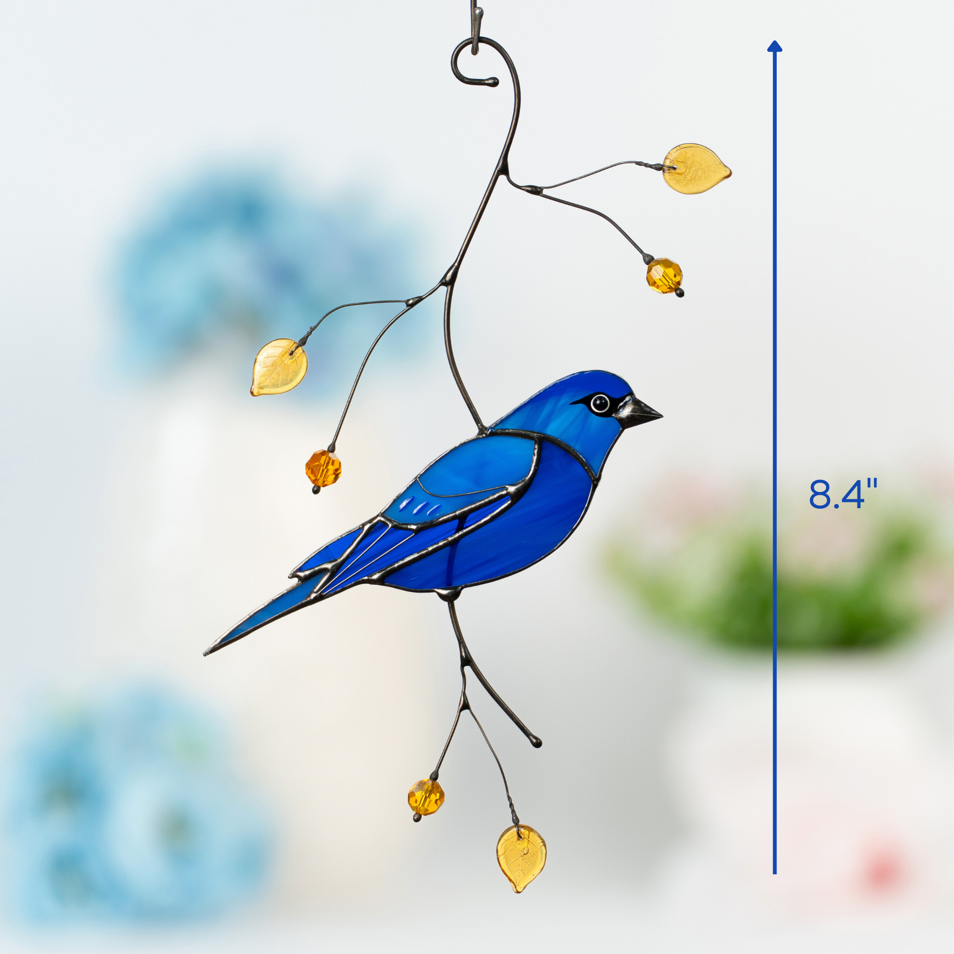 Stained glass indigo bunting bird hanging from branch with yellow beads, symbolizing serenity and artistic harmony with nature.