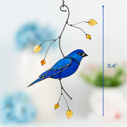 Stained glass indigo bunting bird hanging from branch with yellow beads, symbolizing serenity and artistic harmony with nature.