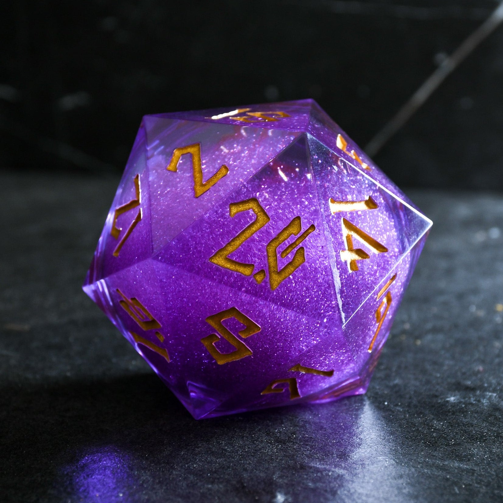 A large, purple, 20-sided die with engraved numbers in gold