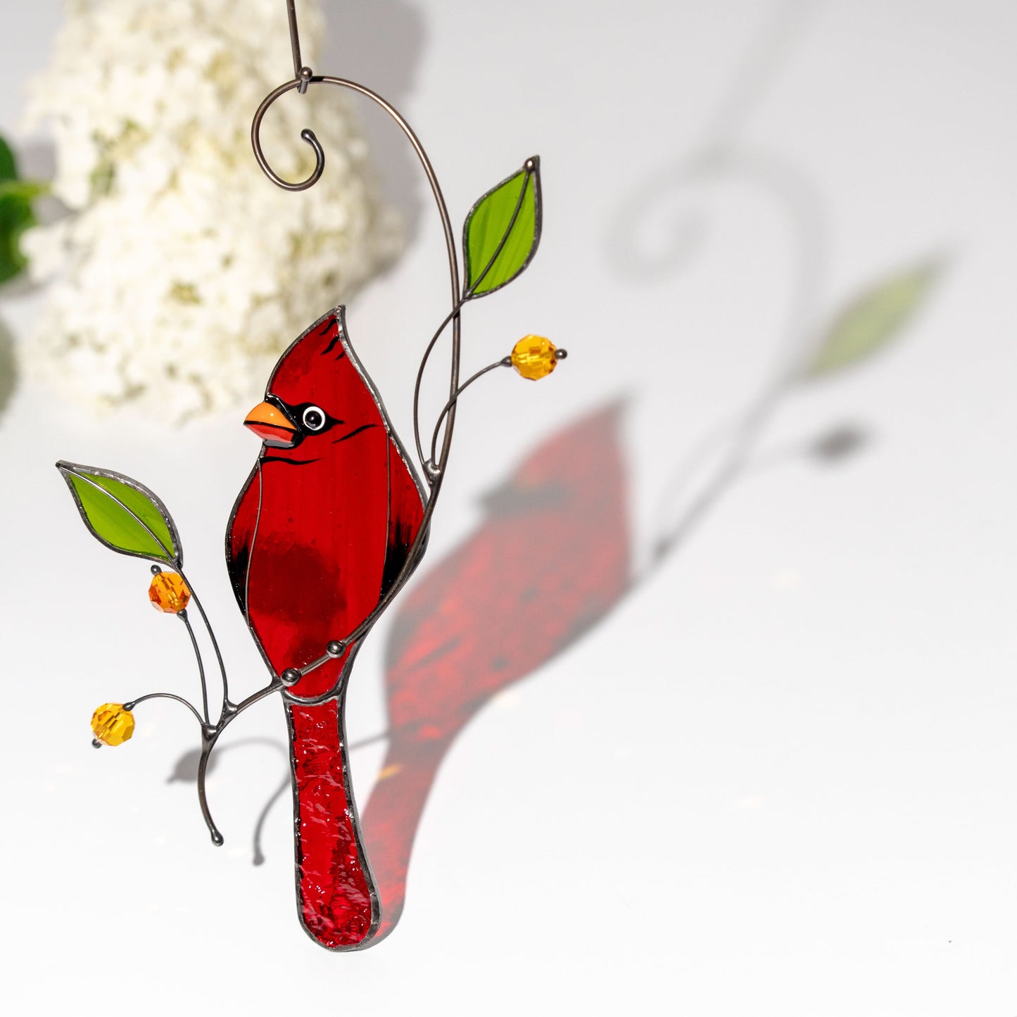 Cardinal suncatcher reflects light on surface, showing clear handmade glass texture and form.