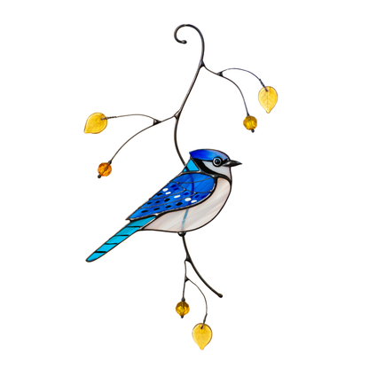 Blue jay stained glass bird perched on a decorative branch with yellow glass leaves, photographed on white background.