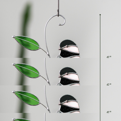 Yellow chickadee suncatcher with black and white head and amber beads hanging from a hook, plant background and 6” label.