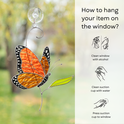 Monarch butterfly suncatcher displayed on a glass window using a suction cup and instruction beside: clean window and suction cup, press a cup to the surface.