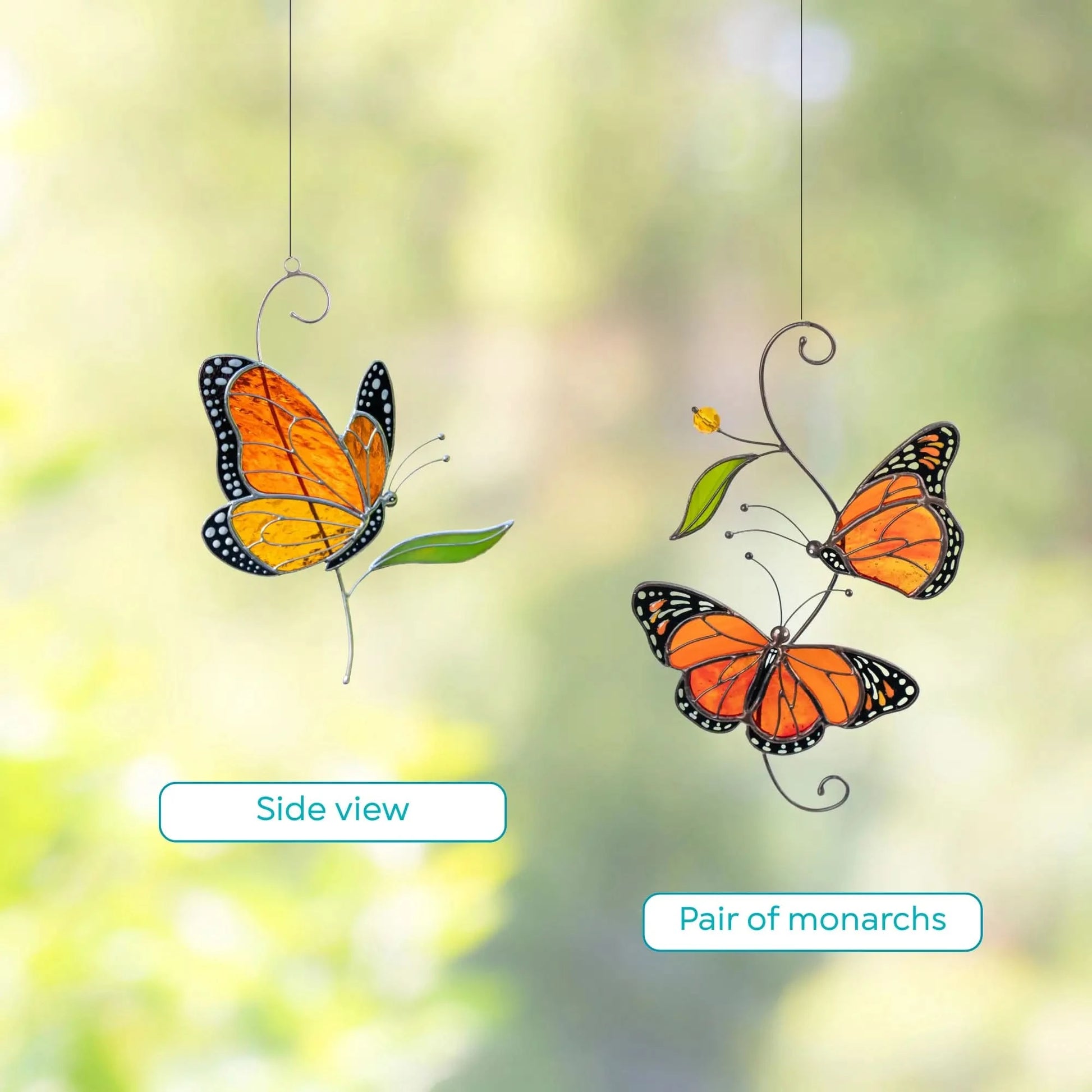 Stained glass monarch butterflies on a branch with leaves against a blurred green background